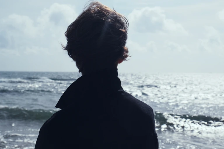 Un jeune homme face à l'océan