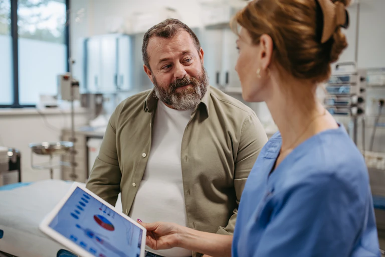 Uma jovem médica conversa com o paciente, um senhor de barba de meia idade
