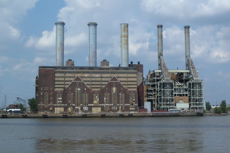 Two large buildings side by side with five massive smokestacks