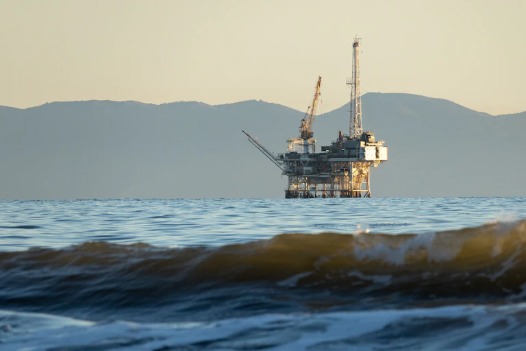 An offshore oil rig with mountains in the background