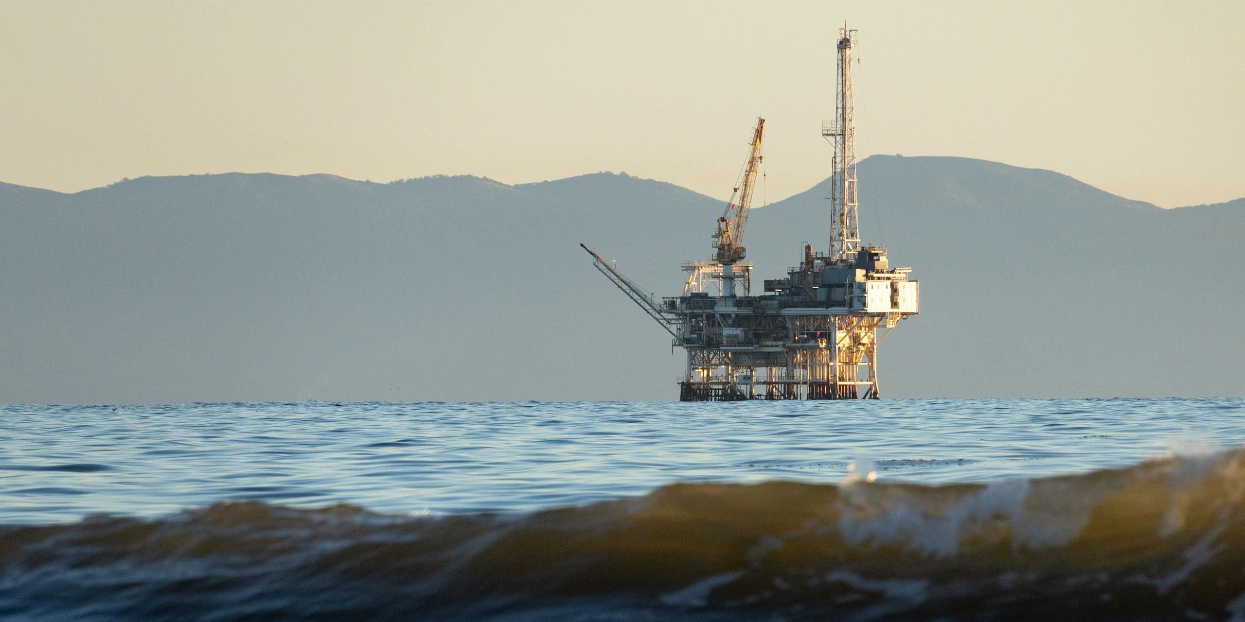 An offshore oil rig with mountains in the background