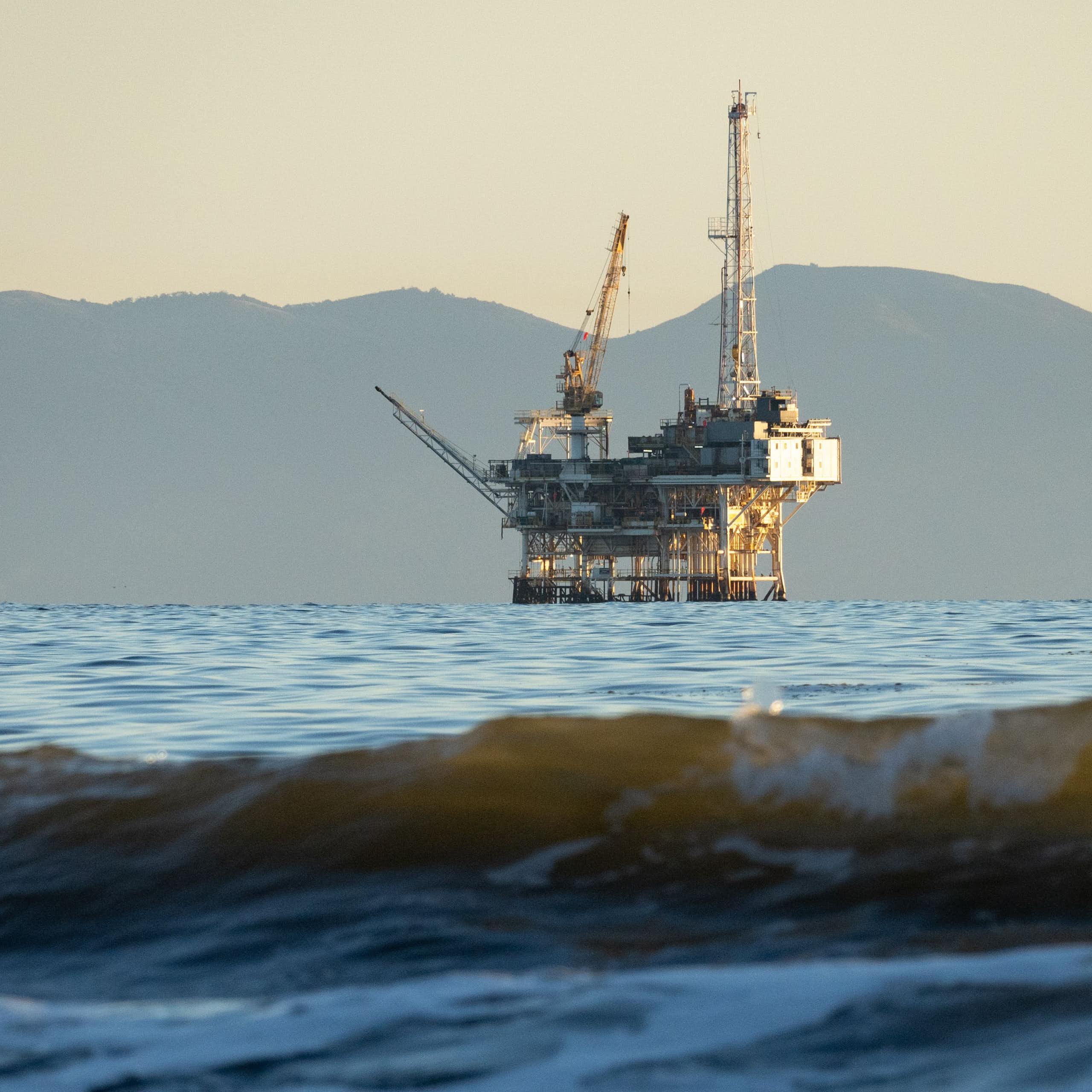 An offshore oil rig with mountains in the background