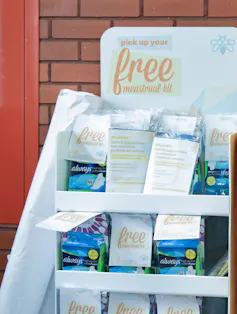 Boxes of mentstrual products on a display in a hallway.
