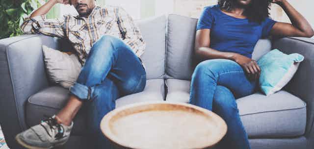 Two people sit apart from each other on a couch