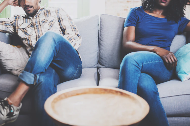 Two people sit apart from each other on a couch