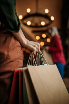 An unrecognisable female hand holding a bunch of shopping bags indoors