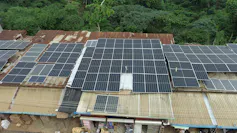 Four buildings with rusty roofs and dozens of solar panels mounted on top