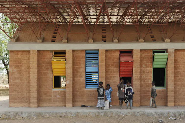 school children standing by building in Africa, double roof