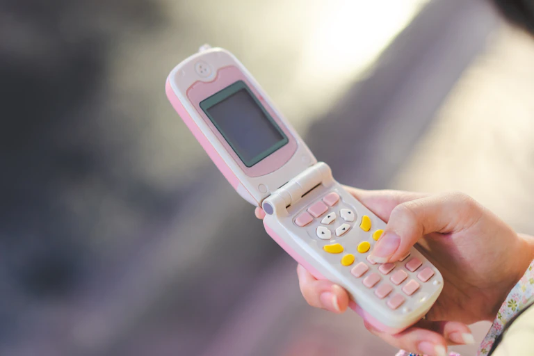 Hand holding pink and white flip phone