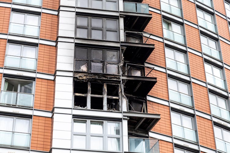 Três sacadas queimadas na lateral de um prédio revestido.