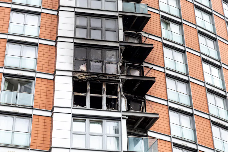 Three burnt out balconies on the side of a cladded building.