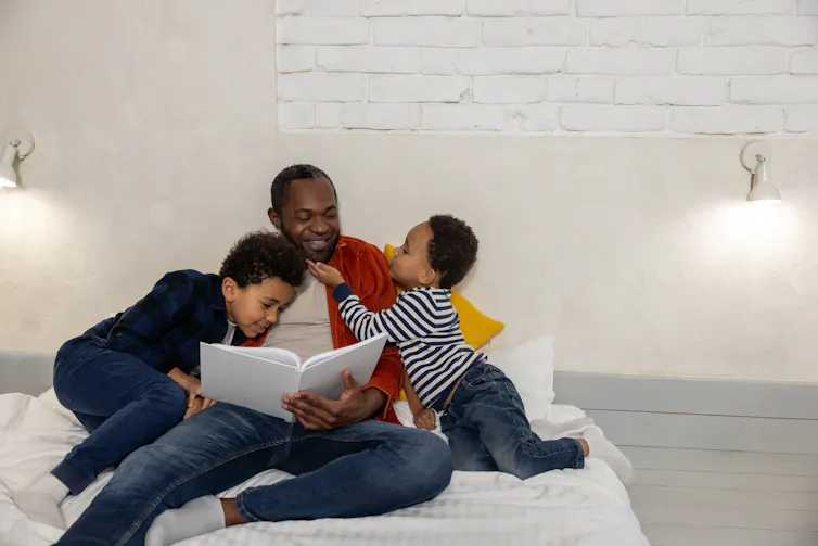 Dad and two sons looking at book together
