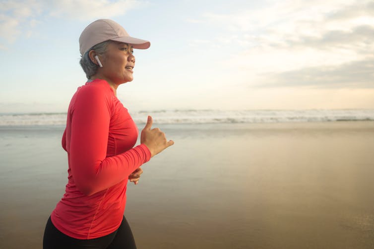 A middle-aged woman runs on a beach.