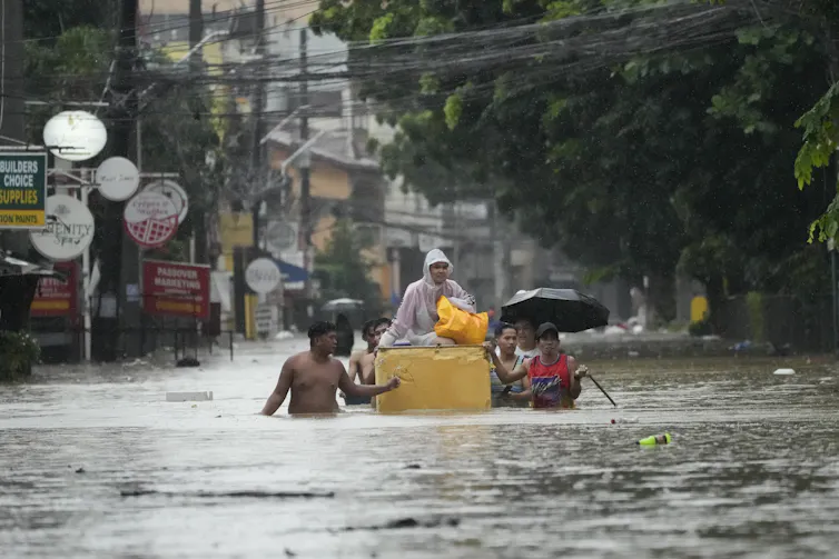 People wade through a flooded street.
