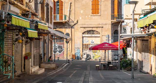 An empty street where the shops are boarded up.