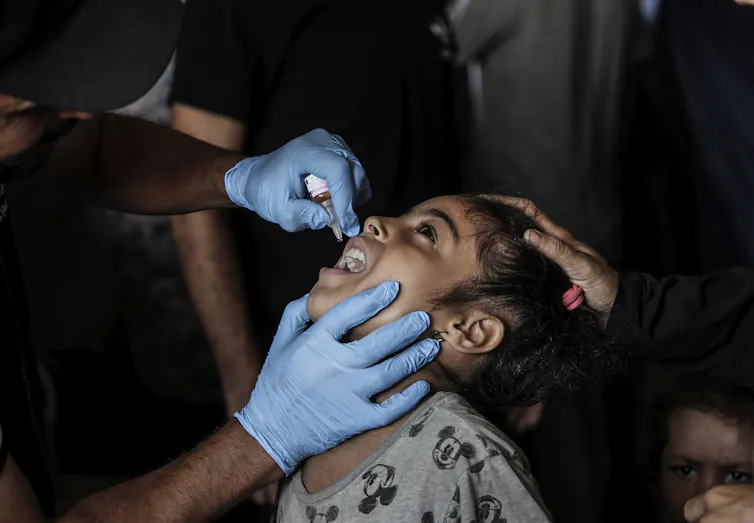 A nurse administers polio vaccine drops to a Palestinian child.