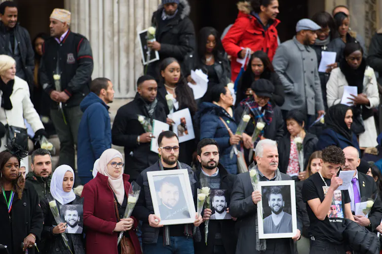 People leaving a church carrying framed photos of Grenfell victims.