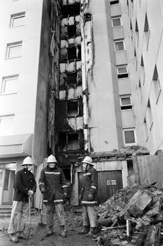 Firefighters standing outside a burnt out block of flats