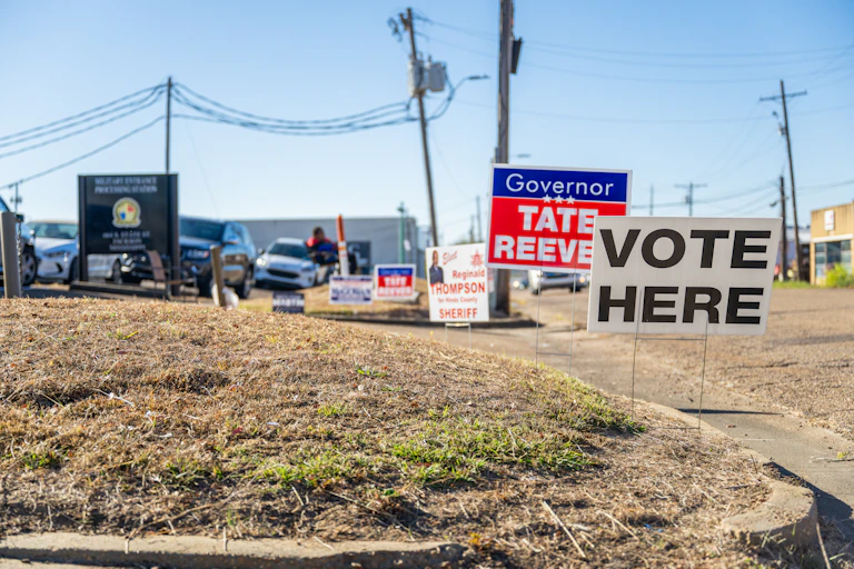 A sign reading Vote Here is seen in a desolate neighborhood.