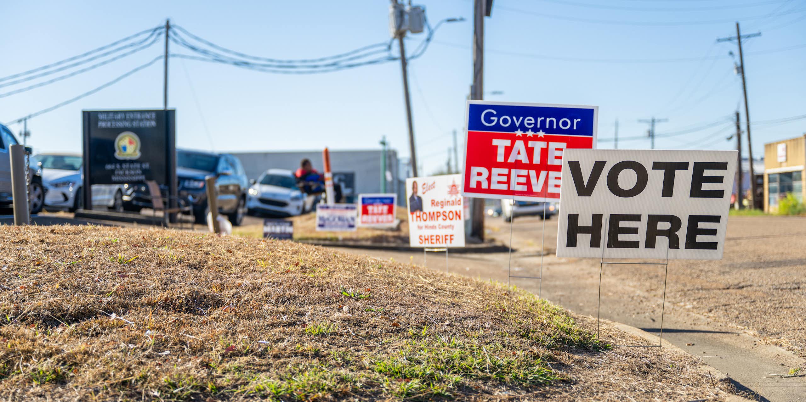 A sign reading Vote Here is seen in a desolate neighborhood.