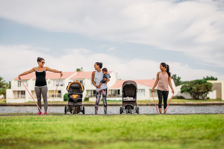 Women exercising in a park with their kids in strollers