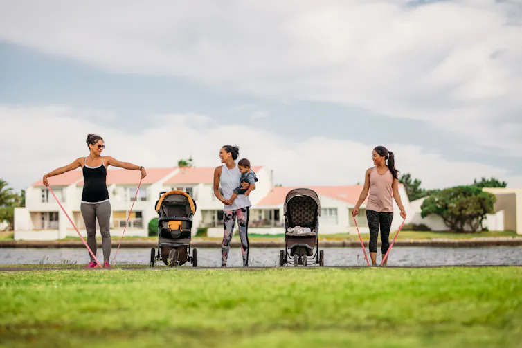 Women exercising in a park with their kids in strollers