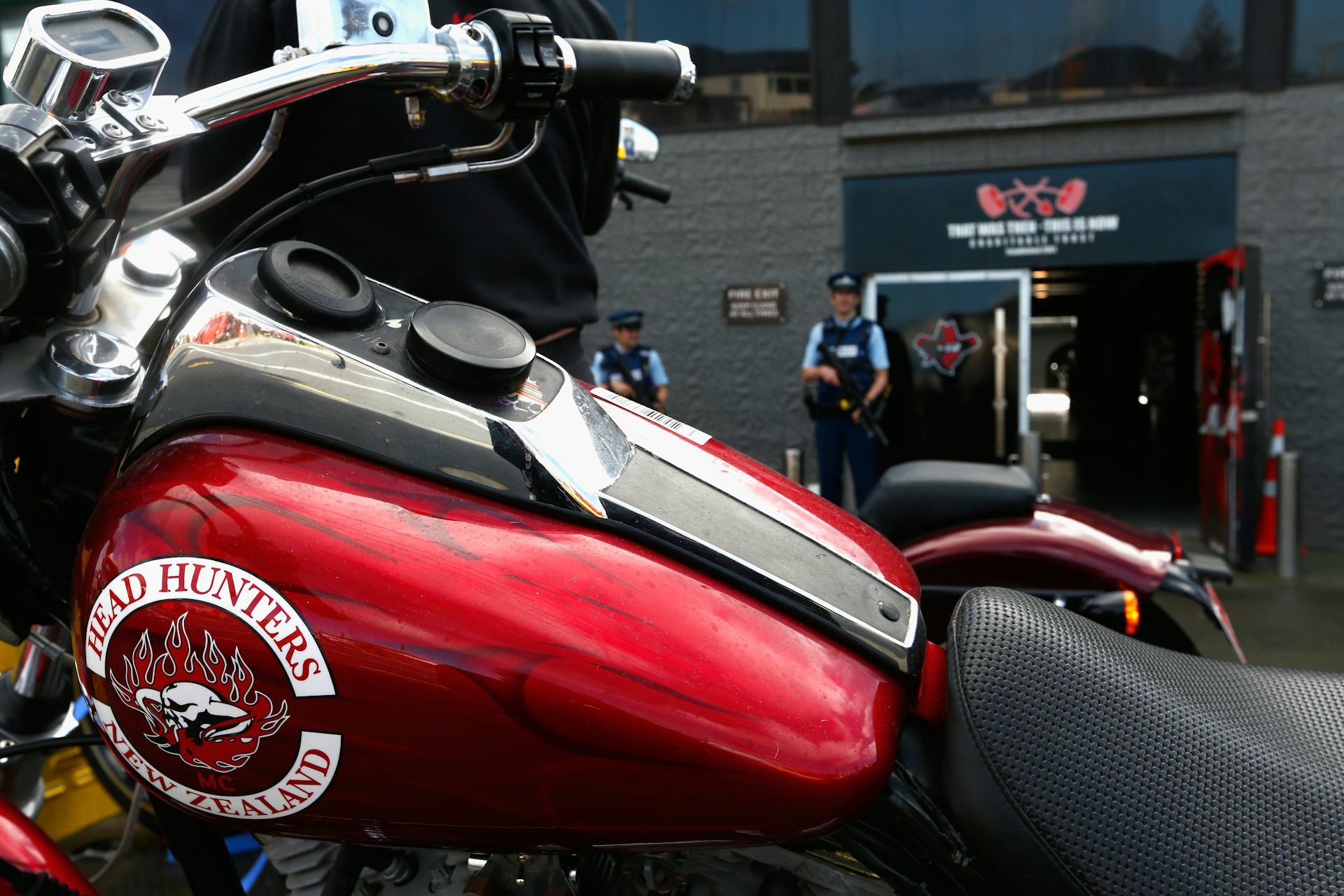 Armed police stand guard as confiscated motorcycles are removed from a boxing gym run by the Head Hunters gang.