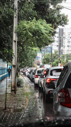 A curved street lined wth trees and cars, apartment blocks in the background.