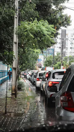A curved street lined wth trees and cars, apartment blocks in the background.