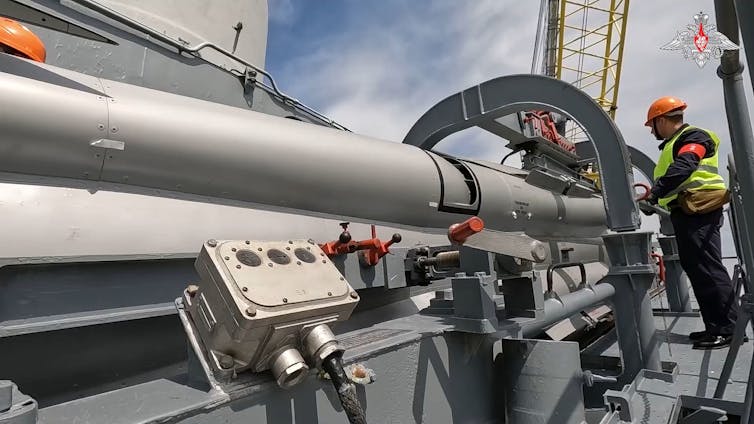 Russian troops load a cruise missile onboard a warship.