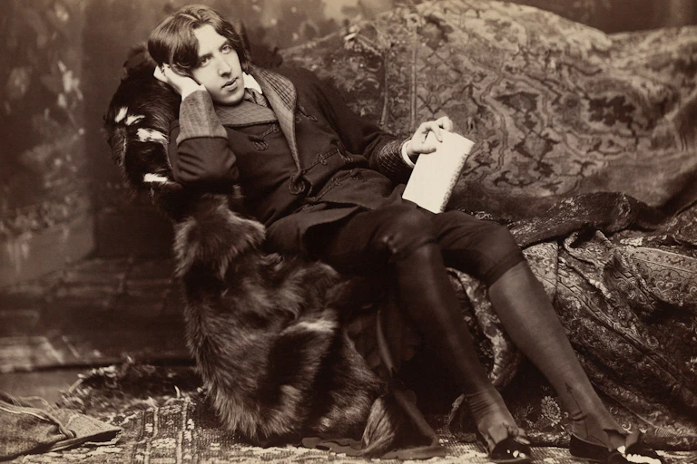 Oscar Wilde lying on a couch and holding a book