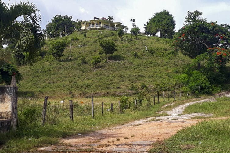 A house is seen on the top of a grassy hill.