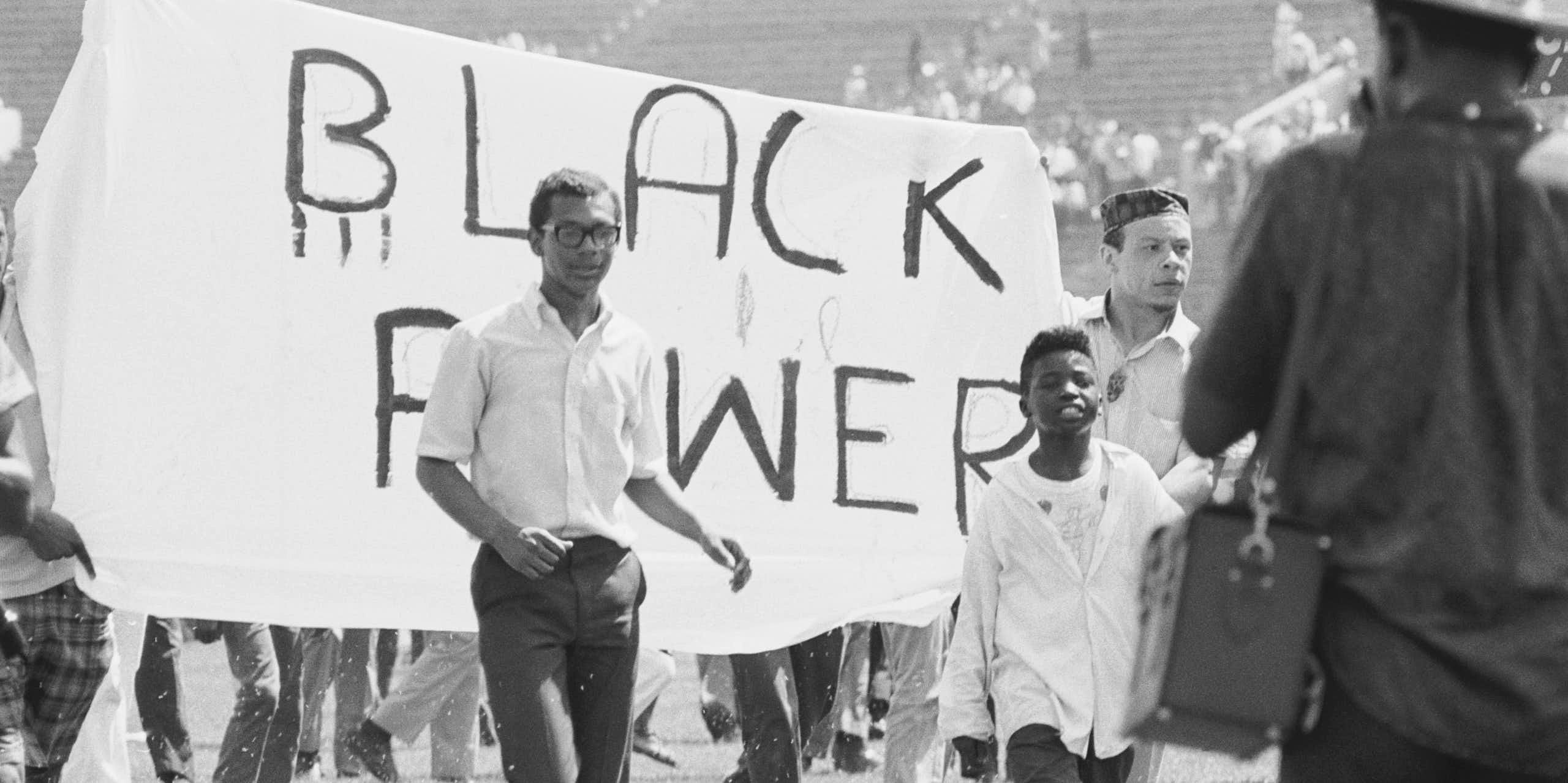Young Black men holding a banner which says 'Black Power," as they march.