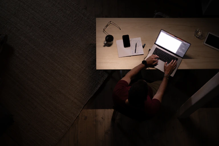 A high-angle view of male graphic designer working on a computer late at night in his home office.