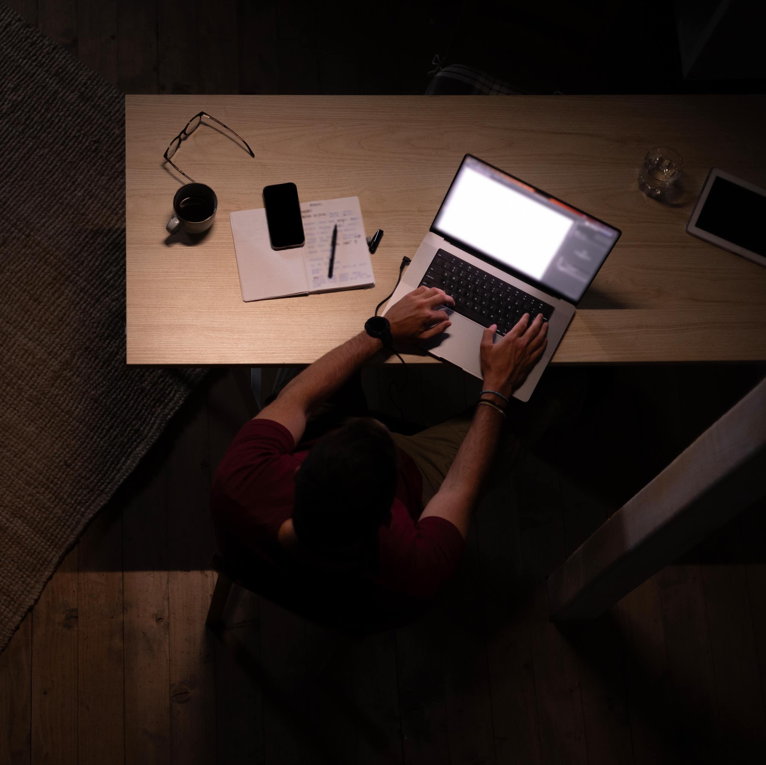 A high-angle view of male graphic designer working on a computer late at night in his home office.