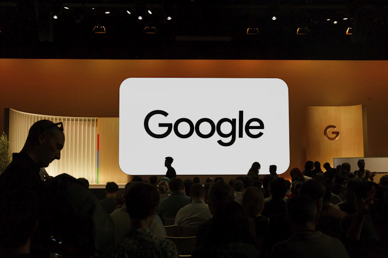 Audience members gather in front of large Google sign for new product announcements.