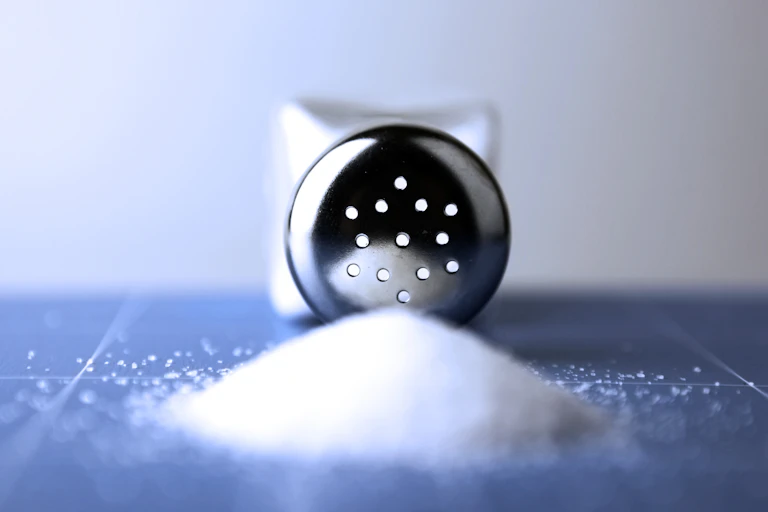 A salt shaker lying on a table with holes facing the camera in close up.