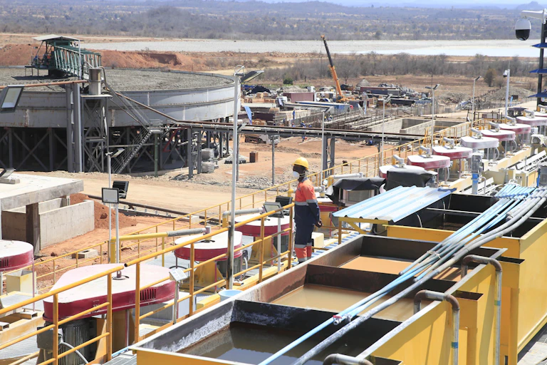 A worker seen from a distance standing atop mining equipment.