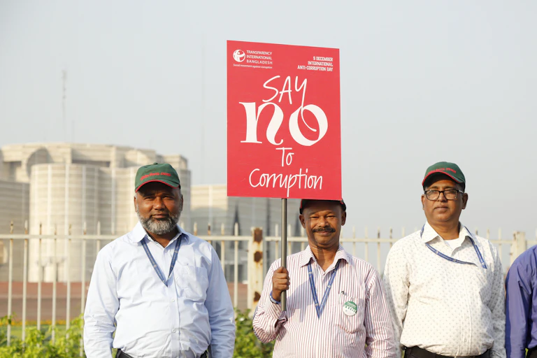 Four Bangladeshi men holding a red placard reading: 'Say no to corruption".