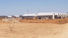 A row of houses crowded together on dusty red sand