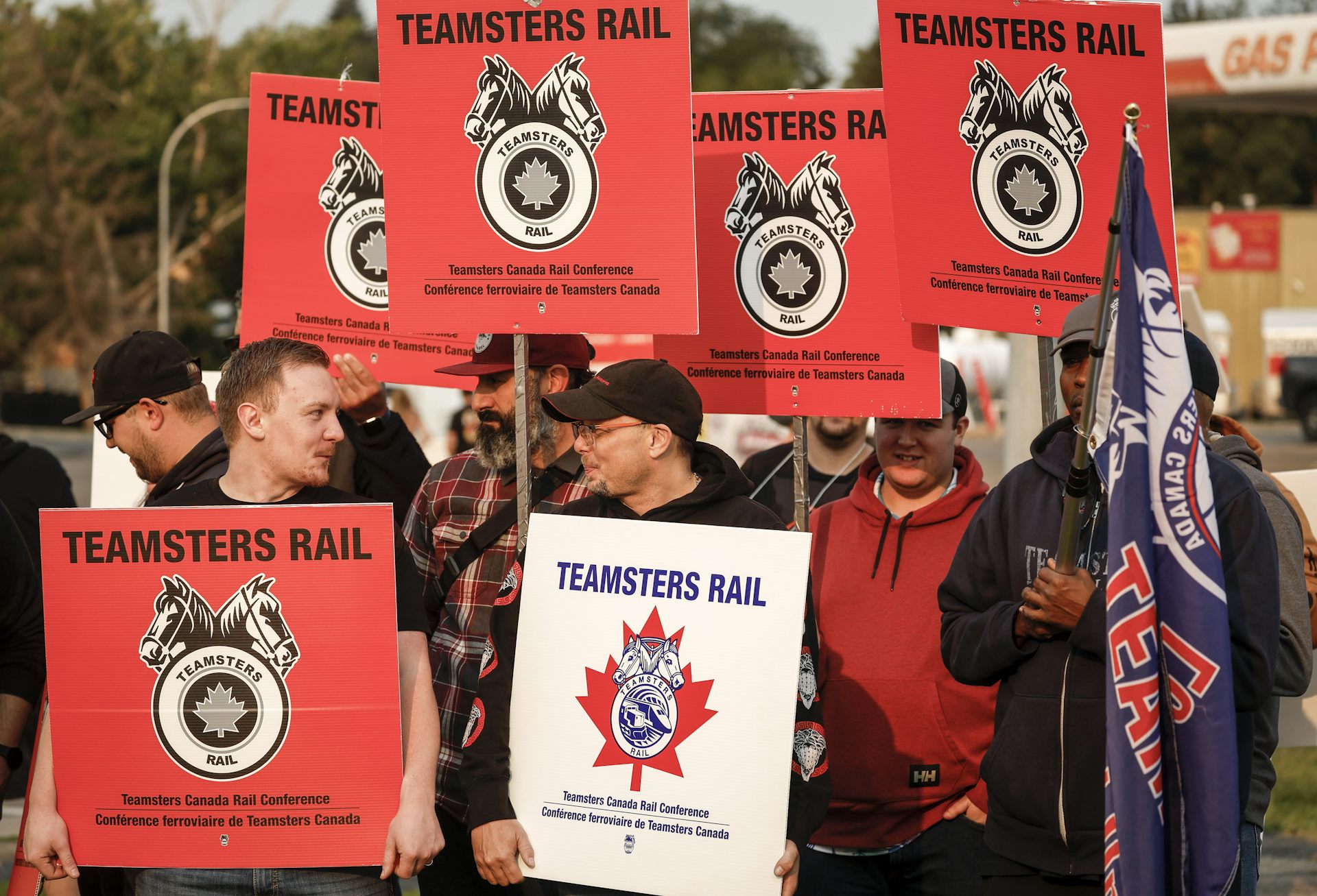 A group of people hold protest signs that say 'Teamsters Rail'