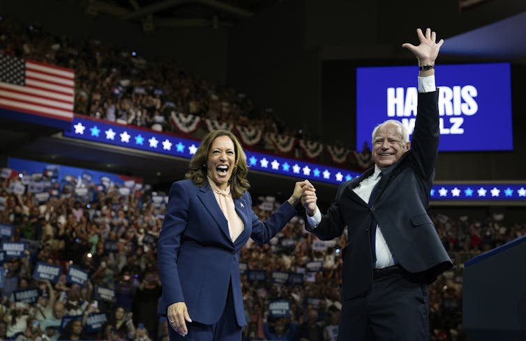 Democratic presidential nominee Vice President Kamala Harris and her running mate Gov. Tim Walz smiling broadly on a stage.