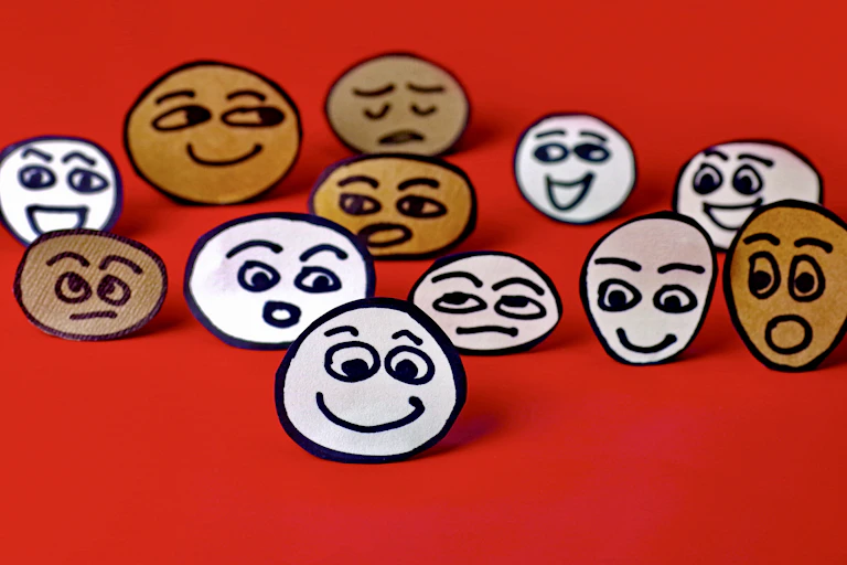 Illustrated image of cut-out paper smiley faces, some happy, some sad, some bored