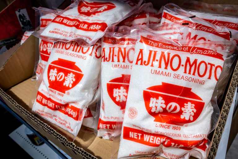 Red and white packets of MSG on a shelf.
