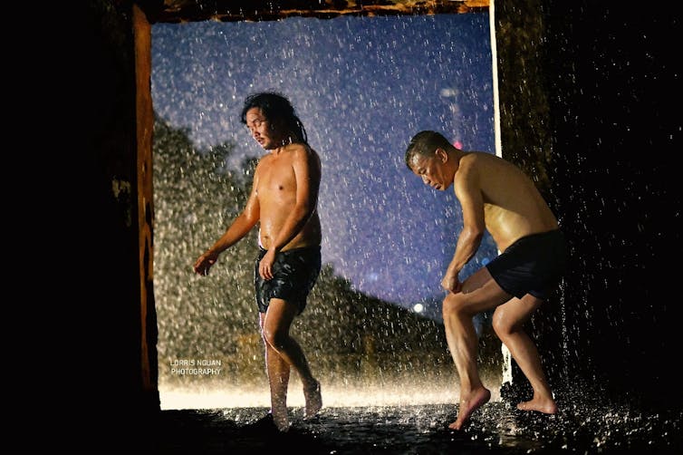 Two men dance in the rain.