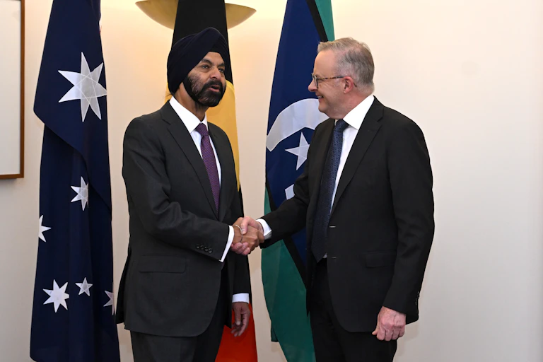 Two men in suits, one wearing a turban, shaking hands