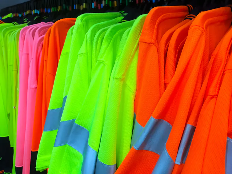 Safety vests on a stand, yellow, pink and orange with retroreflective stripes