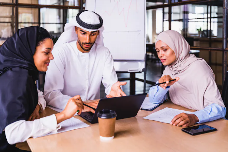 Two women and one man from the Middle East talking during a corporate business team meeting.