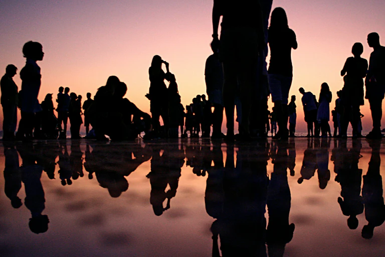 Silhouettes de gens se tenant sur une plage au crépuscule.