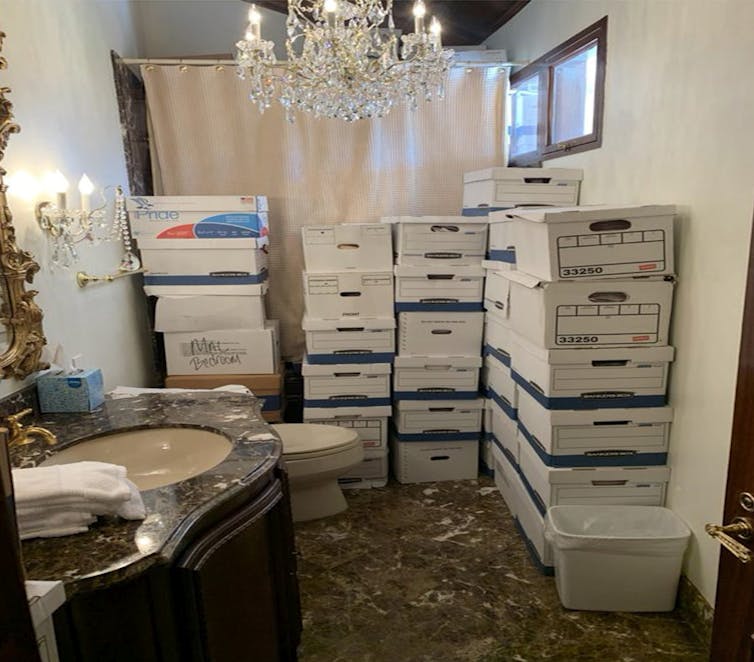 Boxes of documents are stacked in a bathroom.